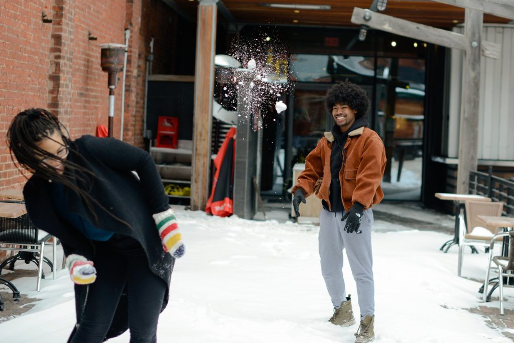 smiling man throwing snowball at woman