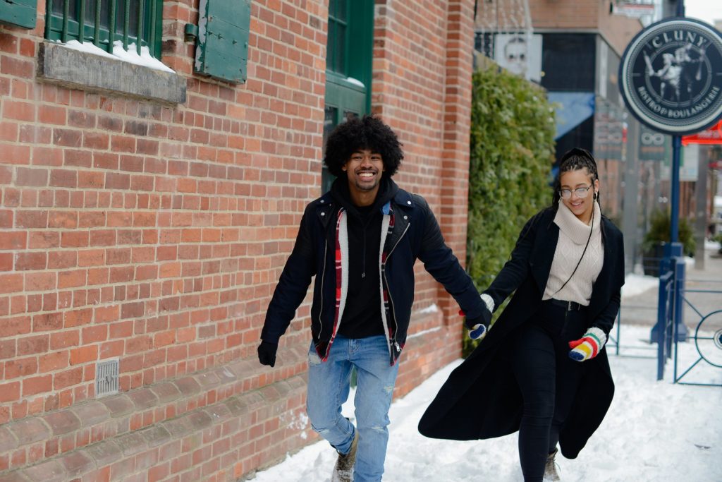 couple walking and laughing in snow at engagement photoshoot