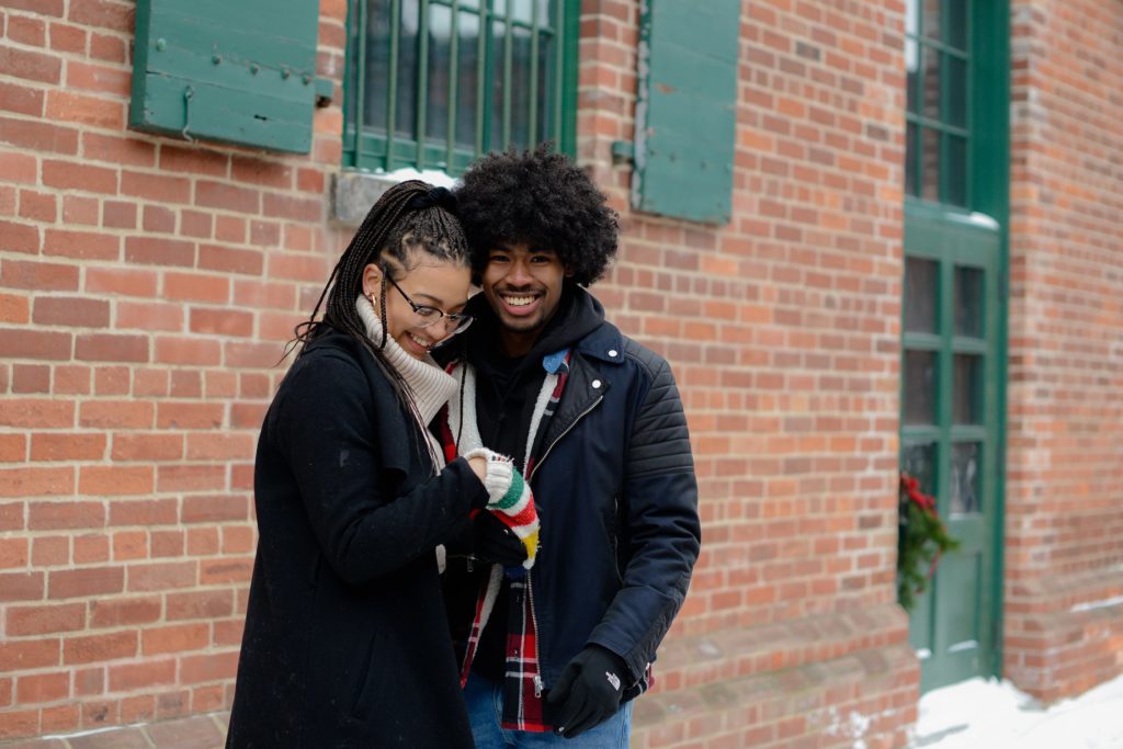 smiling couple against brick wall for engagement photography session