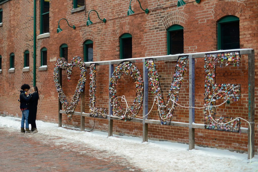 couple hugging near sign that reads LOVE at engagement photography session