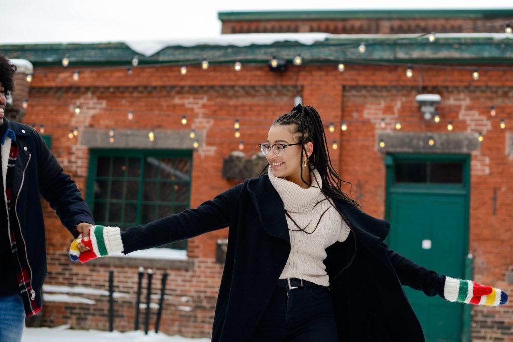 woman posing in the snow holding a man's hand 