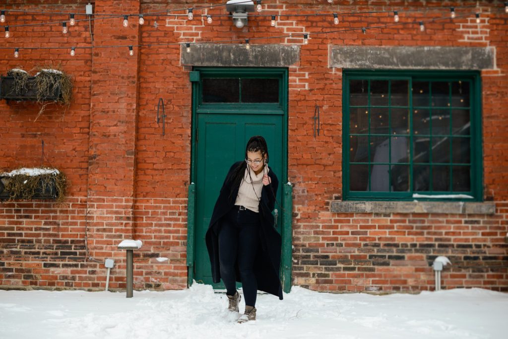 woman posing in snow in front of green door and brick wall