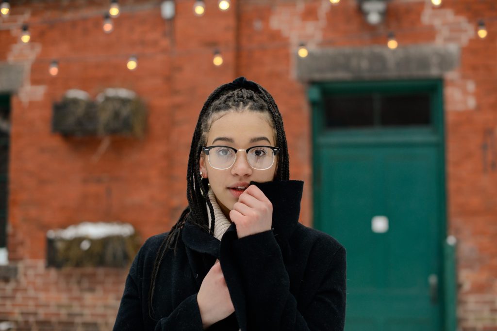 woman in glasses looking at camera against red brick wall