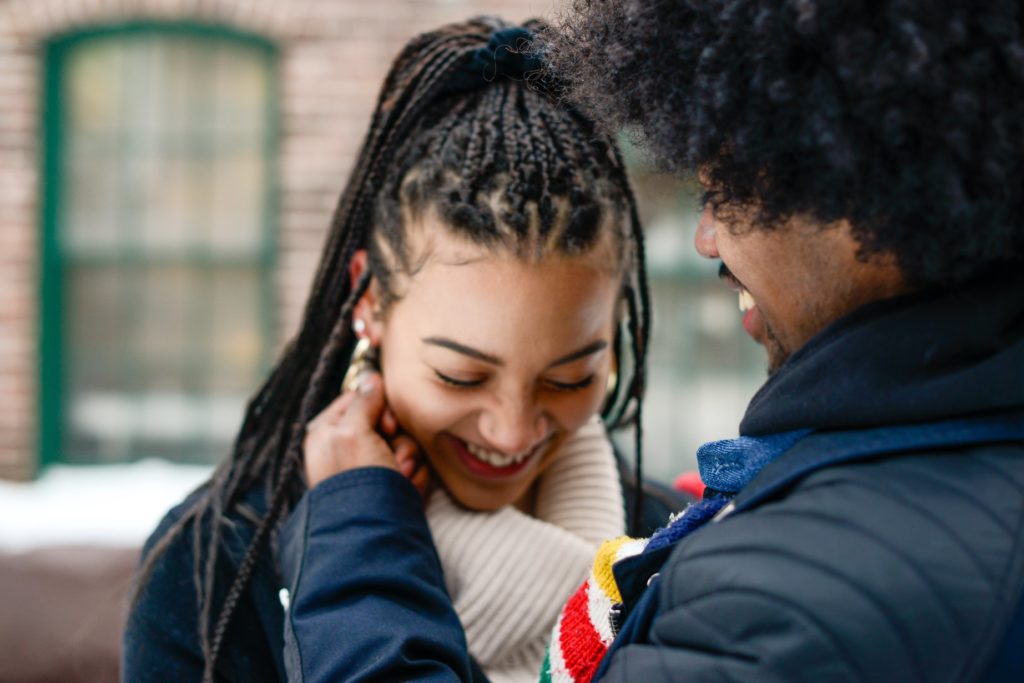 man touching laughing woman's face at an engagement photoshoot