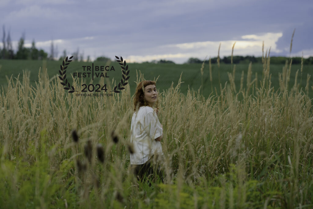 Britt Lower playing Miriam Gordon in Darkest Miriam stands in overgrown fields for the Tribeca Film Festival nomination poster