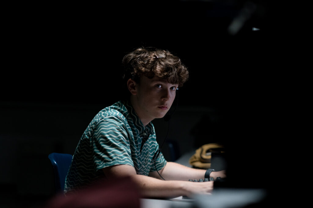 Jack Fulton typing on a computer in. dark room in an episode of Detention Adventure