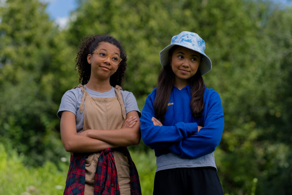 Simone Miller and Alina Prijono talk to each other outside while at Island summer camp in an episode of Detention Adventure