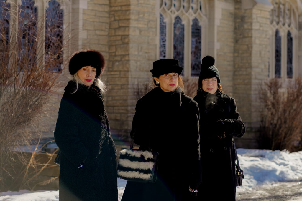 Jocelyne Zucco, Katherine Trowell, Anna Migliarisi stand outside of the church starring in a judgmental way in a scene from T.A.R.T