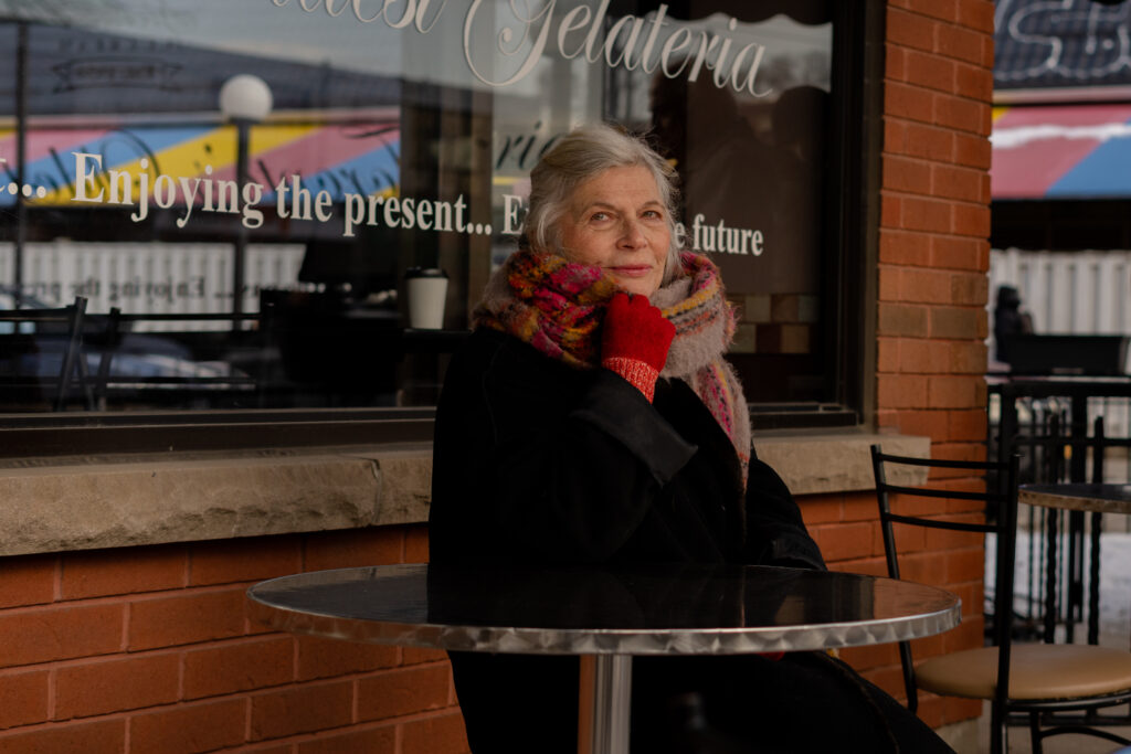 Trudy Weiss sits infront of bakery in a scene from T.A.R.T
