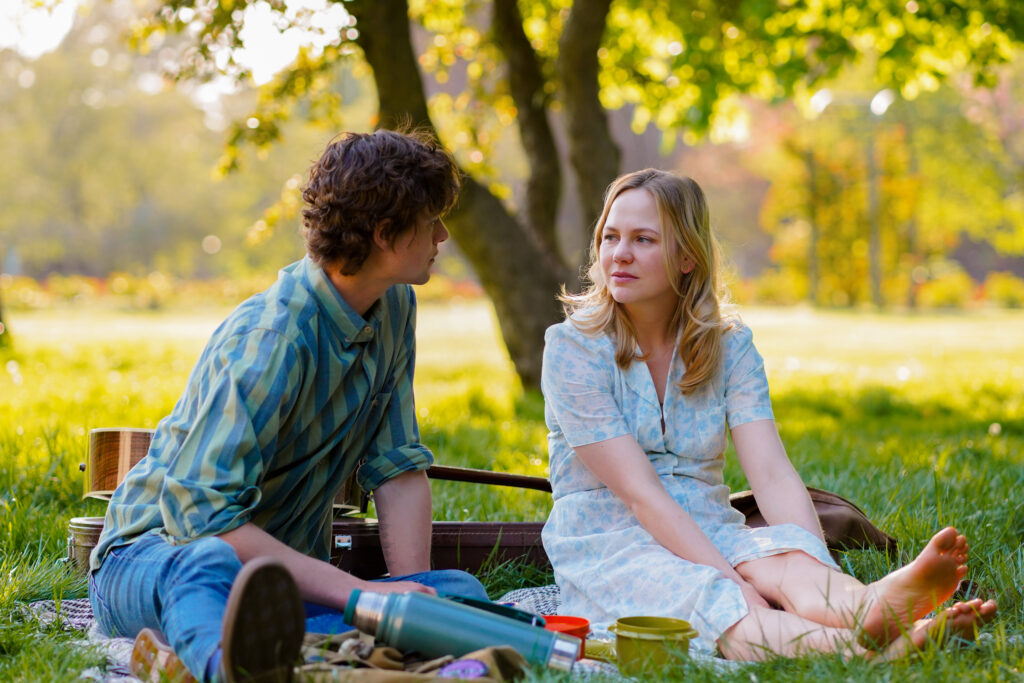 Adelaide Clemens sits having a picnic with Douglas Smith in a park in a scene from The Swearing Jar