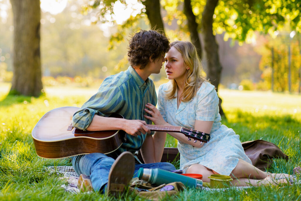 Adelaide Clemens sits having a picnic with Douglas Smith in a park in a scene from The Swearing Jar
