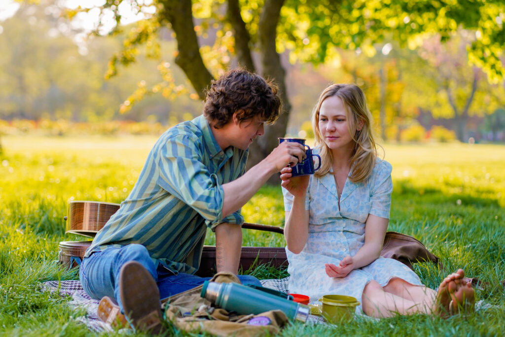 Adelaide Clemens sits having a picnic with Douglas Smith in a park in a scene from The Swearing Jar