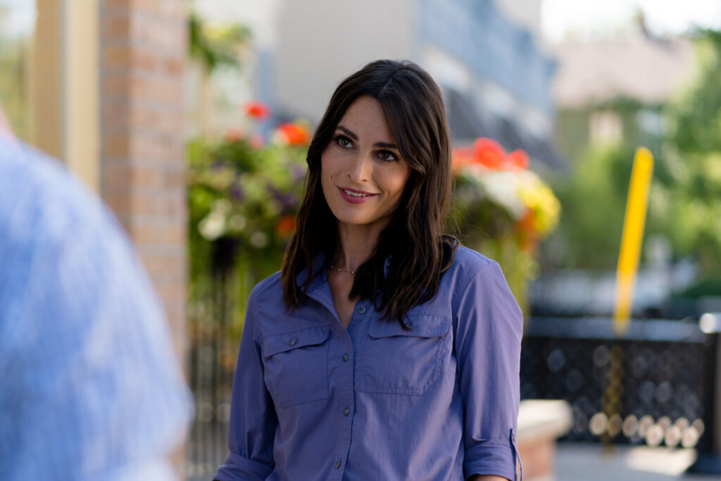 Nola Martin smiles as she chats with a friend in Love in Wolf Creek, a Hallmark movie