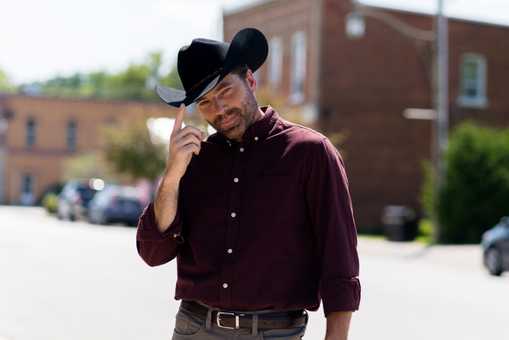 Tim Rozon dips his cowboy hat as he poses for a stills photo in Love in Wolf Creek, a Hallmark movie