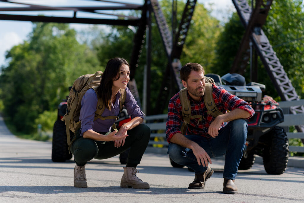 London UK Stills Photographer - Nola Martin and Tim Rozon crouch down on a bridge to see where a lost wolf has gone in Love in Wolf Creek, a Hallmark movie