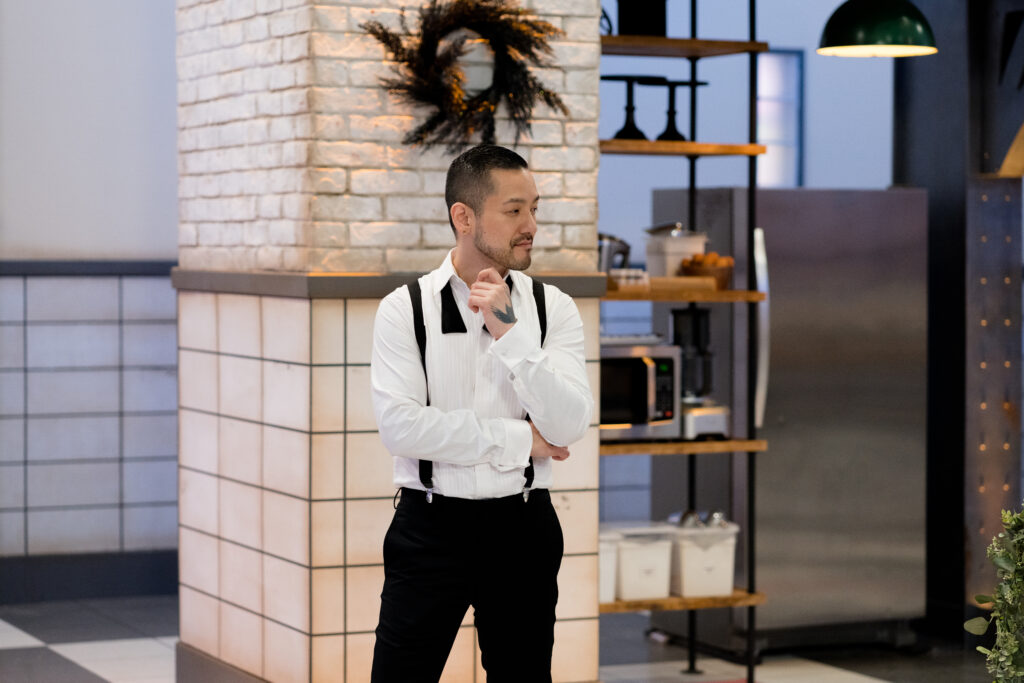 Chef Andrew Han stands and watches Cross Country Cake Off contestants bake