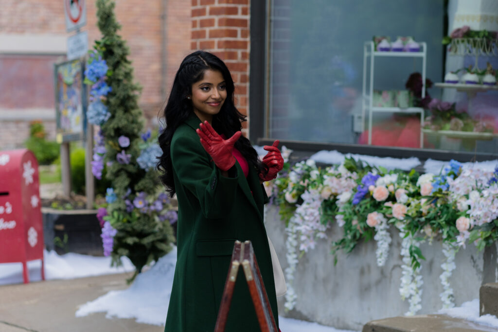 Sugenja Sri waves hello in green winter coat in Hallmark movie, Christmas Lucky Charm