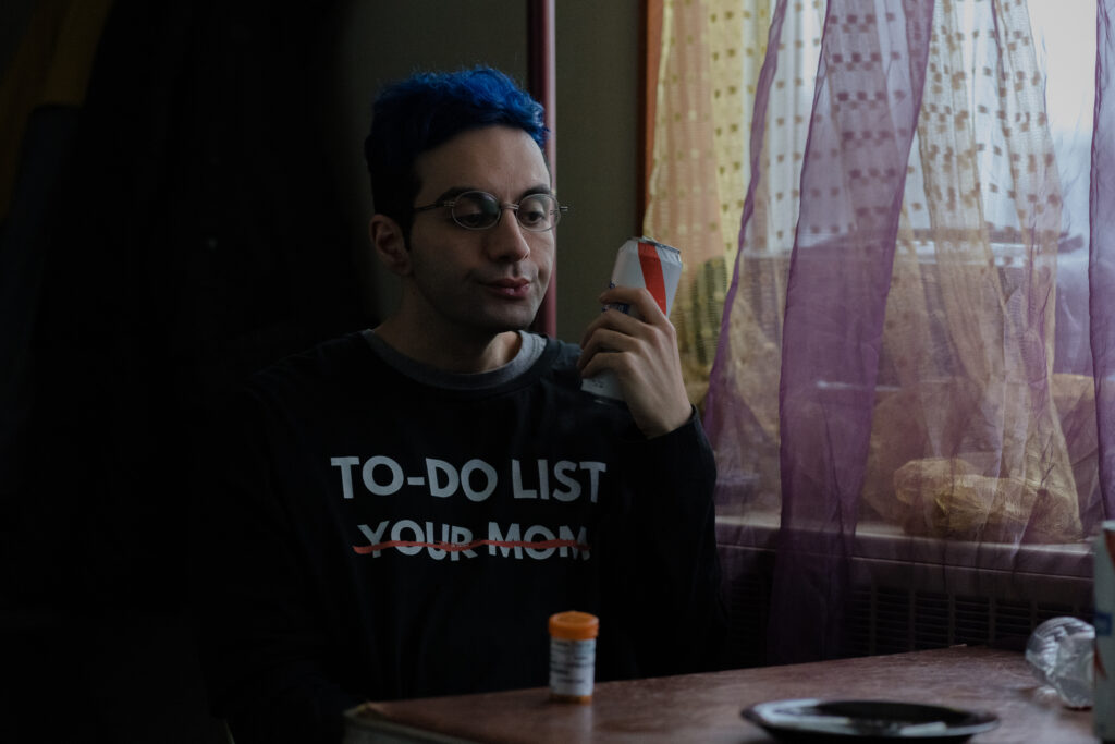 Bobby Summers is talking on the phone wearing a jumper that says To do list: Your Mom, with Your Mom crossed out in a scene from I Hate People, People Hate Me