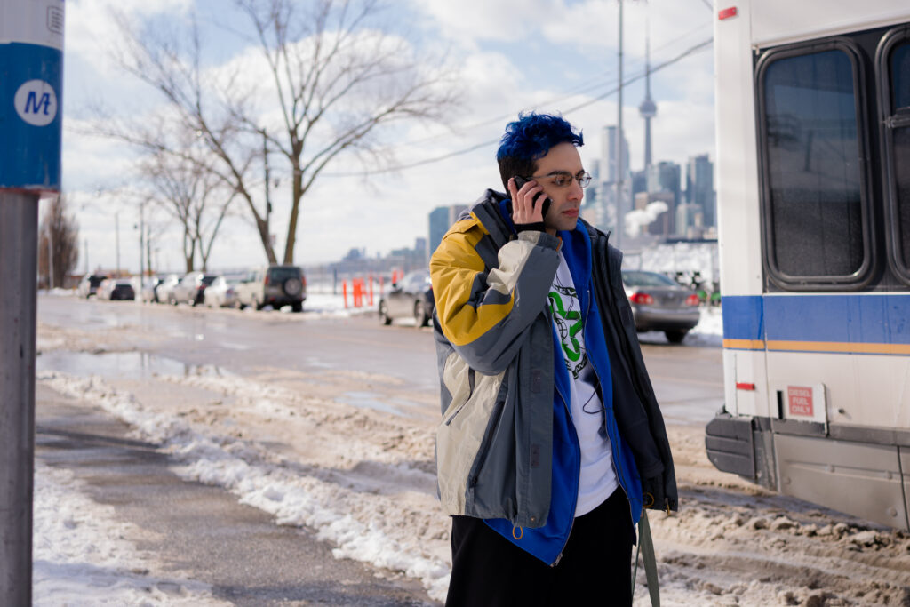 Bobby Summers walks through snow covered streets on the phone in a scene from I Hate People, People Hate Me