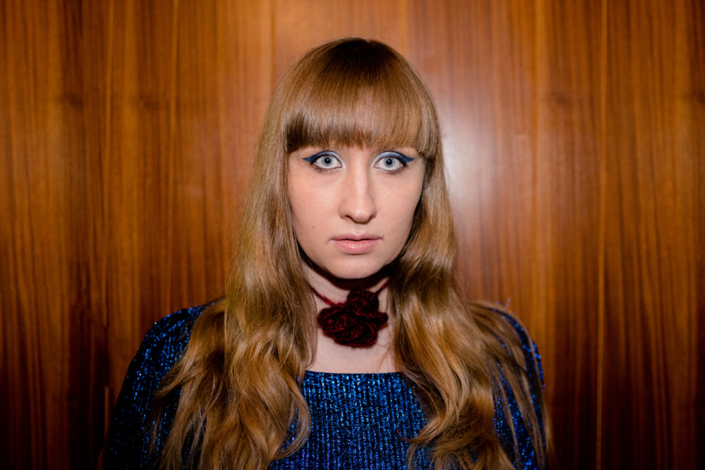 Lily Kaziemiera poses for a party polaroid style photo in a scene from I Hate People, People Hate Me