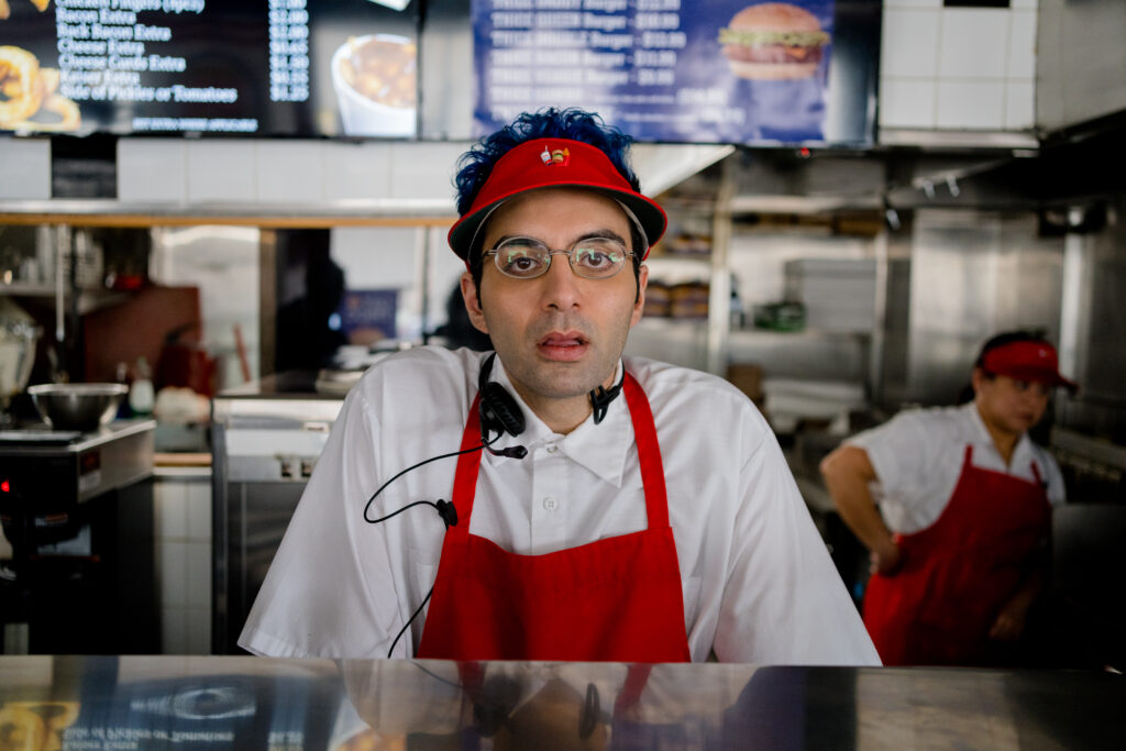 Bobby Summers looks to camera in his take away outfit at the burger joint he works at in a scene from I Hate People, People Hate Me