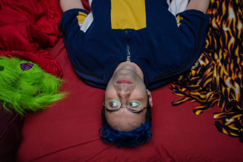 Aerial view of Bobby Summers lying on a bed looking at to the camera in a scene from I Hate People, People Hate Me