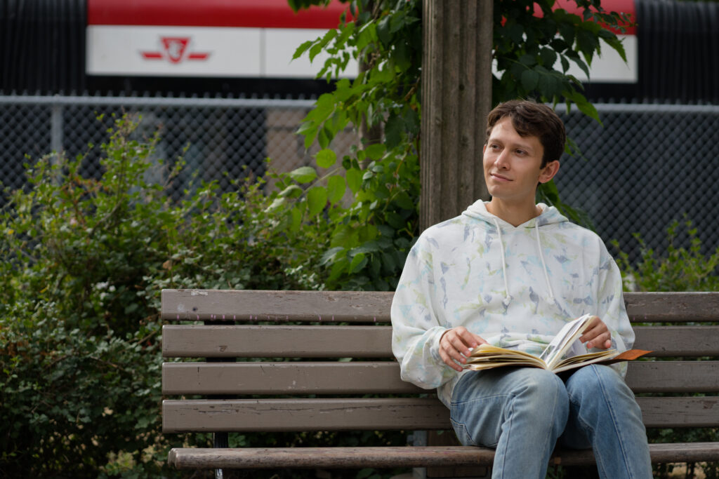 Ryan Ali sits pensively on a bus with his notebook in a scene from the movie Queen Tut