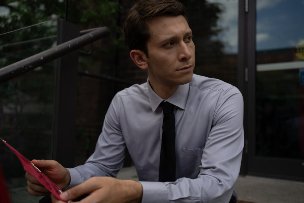 Ryan Ali sits on the stairs outside his church somber in a scene from the movie Queen Tut