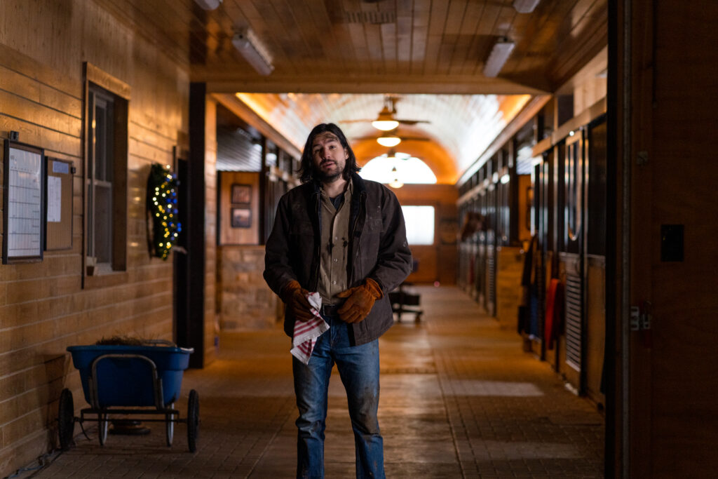 Craig Stickland stands in the stables looking straight to camera in stills photo from Country Hearts Christmas