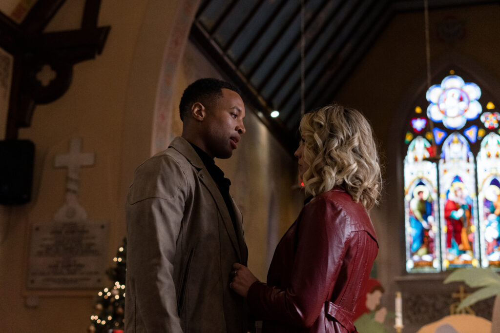 Brendan Morgan and Lanie Mcauley stand closely looking at each other in church Lanie Mcauley and Katerina Maria sing on stage in scene from Country Hearts Christmas