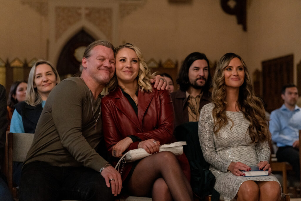Chris Jericho, Lanie Mcauley and Katerina Maria sit in church smiling Lanie Mcauley and Katerina Maria sing on stage in scene from Country Hearts Christmas