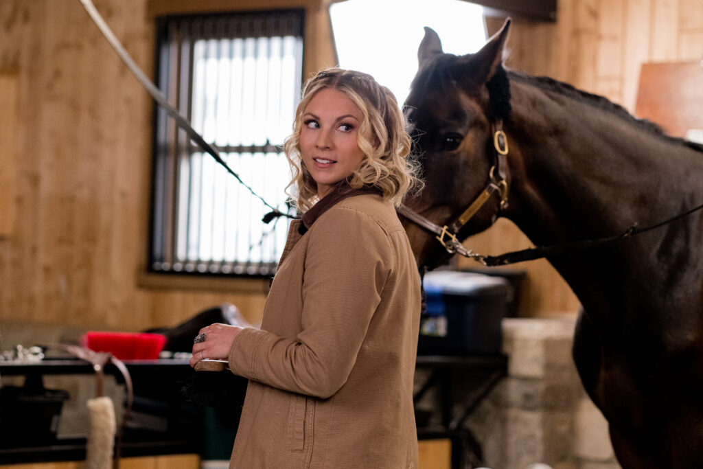 Lanie Mcauley stands in stables looking over her shoulder in scene from Country Hearts Christmas