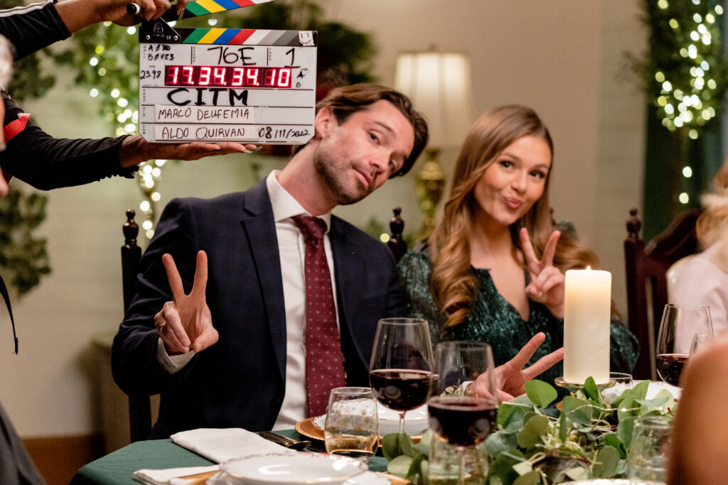 A behind the scenes photo of Joe Scarpellino and Celeste Desjardins filming a scene from the Hallmark movie Christmas with the Knightlys