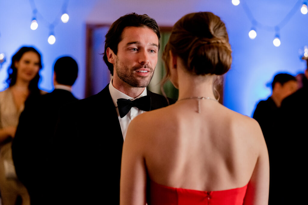 Joe Scarpellino speaks to Celeste in an evening suit in a scene from the Hallmark movie Christmas with the Knightlys