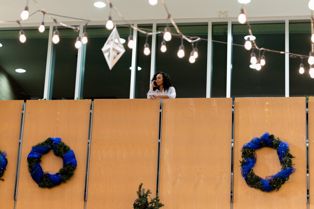 Mishael Morgan stands on balcony floor as she talks on her mobile phone in a scene from Sworn Justice: Taken Before Christmas Hallmark Movie