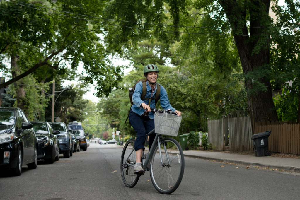 Britt Lower as Miriam rides her bike with a smile on her face