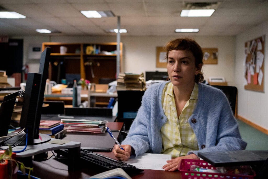 Britt Lower as Miriam sit contemplative at her desk in Darkest Miriam