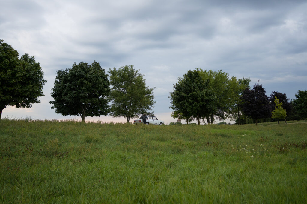 Man stand by car in distance with large field in Darkest Miriam