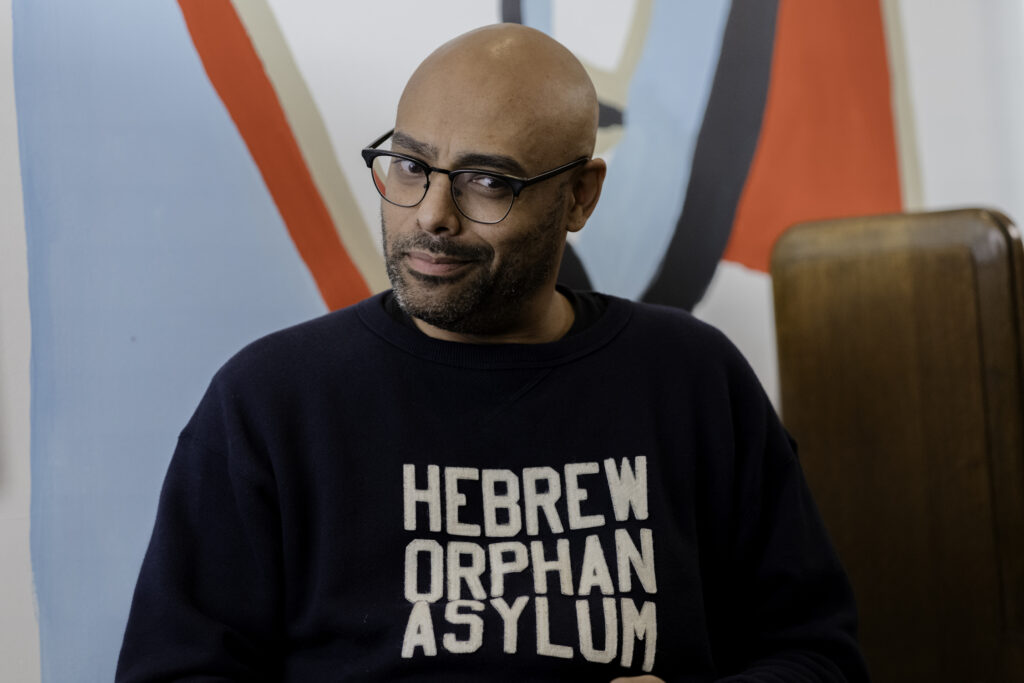 Rainbow Sun Francks smirking with Hebrew Orphan Asylum vintage jumper in My Dead Mom, streaming on Crave Tv.